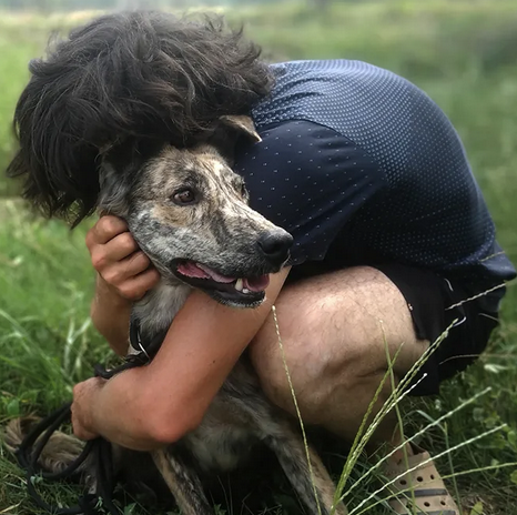 Volunteer hugging a rescued brindle dog in nature